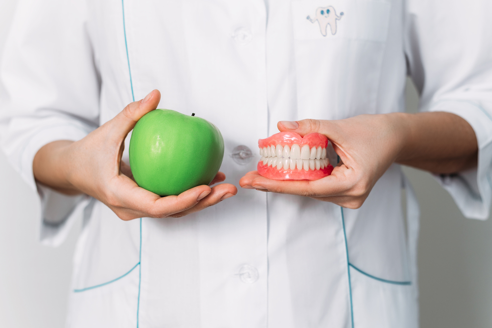 a-false-denture-and-a-green-apple-in-the-hands-of-2025-01-09-12-44-23-utc (1)