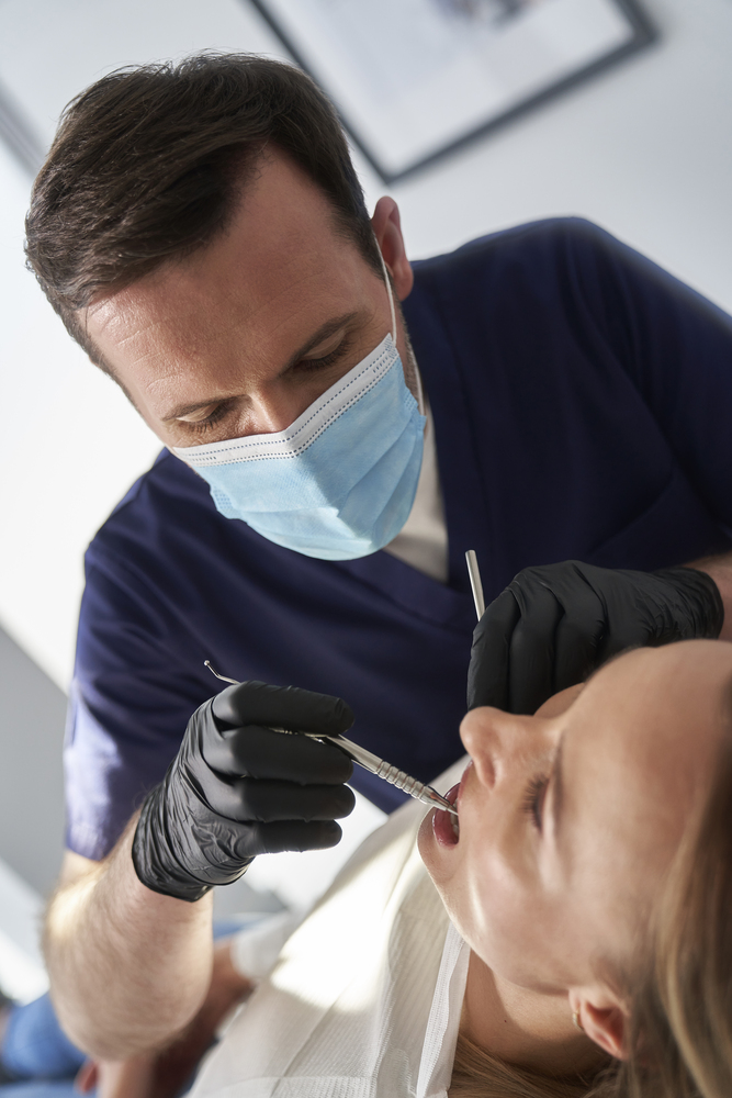 Dentist preparing woman for implant denture Dentist preparing woman for implant denture