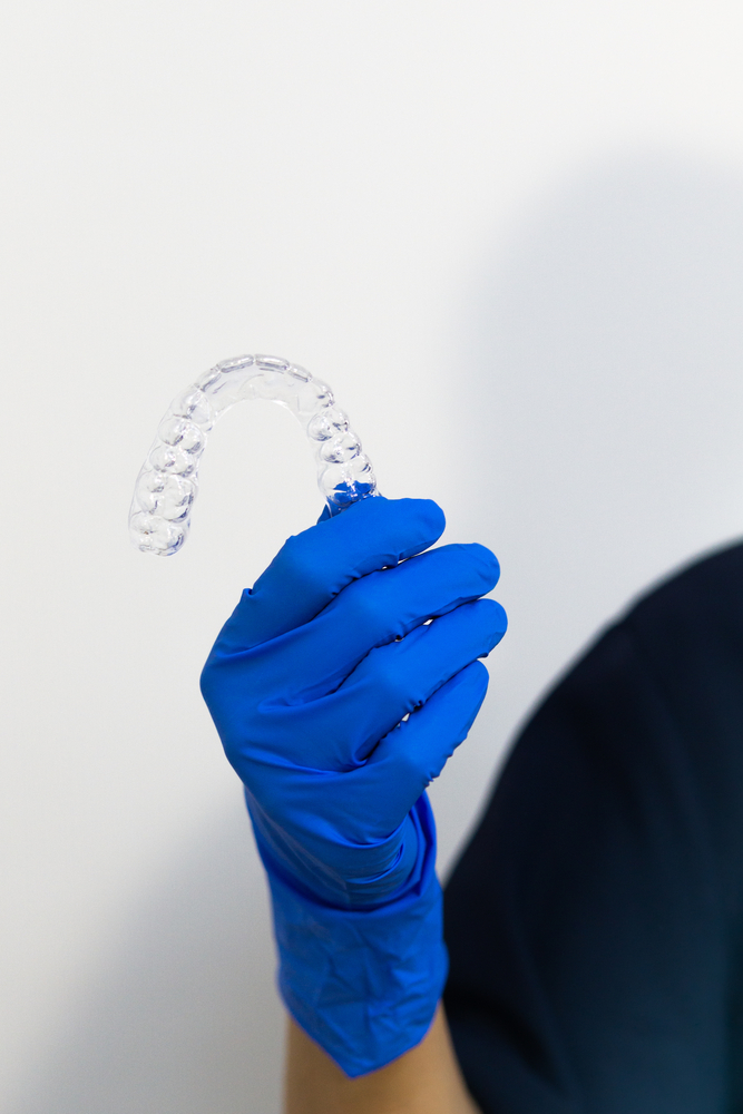 Dentist with gloves holding invisalign